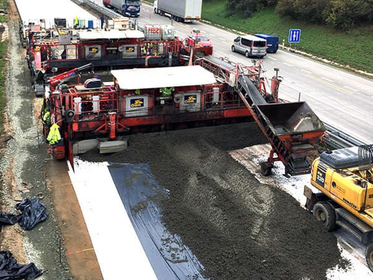 Foto: Zwei Betondeckenfertiger der OEBA beim Betonieren des linken Fahrbahnteils der tschechischen D2, dichter Verkehr auf dem dreispurigen rechten Fahrbahnteil