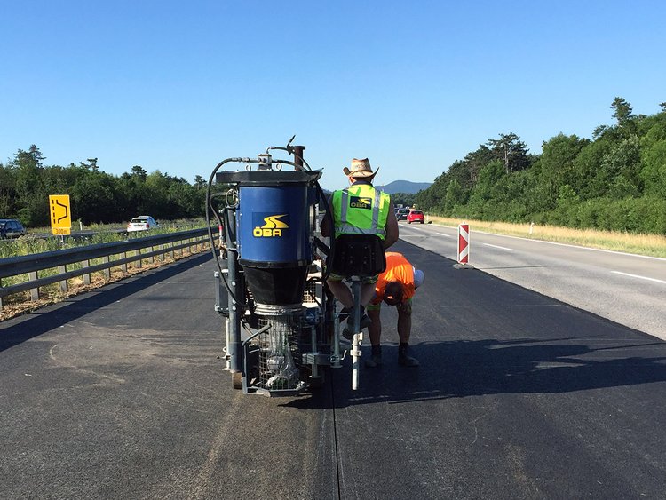 Foto: Arbeiter mit Spezialmaschine auf linkem Fahbahnstreifen einer vierpurigen Autobahn