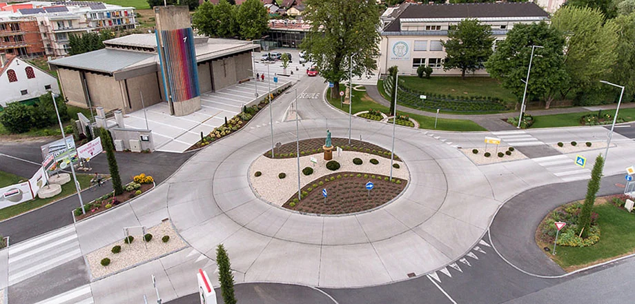 Foto: Neu hergestellter Kreisverkehr aus Vogelperspektive mit deutlich sichtbarem Übergang von Asphalt- auf Betonfläche; im Hintergrund vereinzelte Gebäude umgeben von Grünanlagen