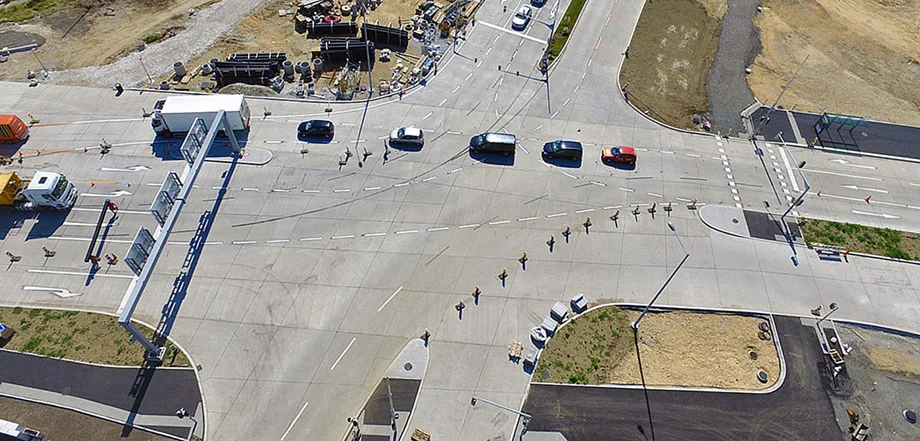 Foto: Innerstädtische Kreuzung umgeben von Baustellenflächen; wenig Verkehr; deutlich erkennbarer Übergang zwischen Asphalt- und Betonoberflächen